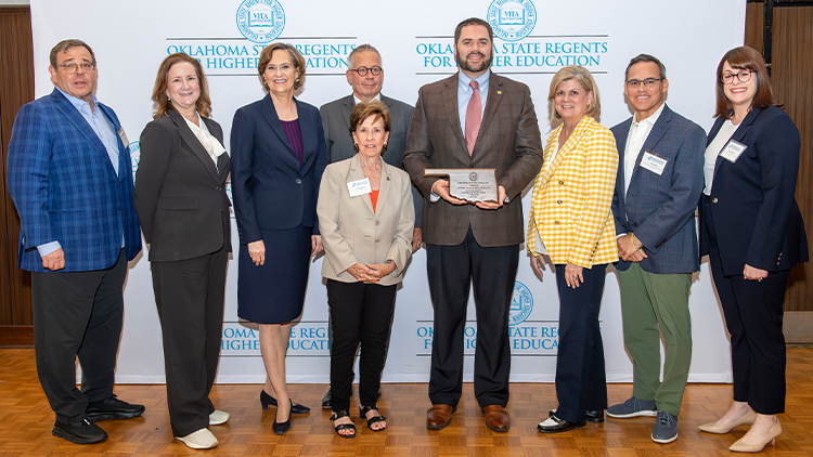 Bankers from First National Bank stand on a stage in Edmond, receiving an Award from USAO.